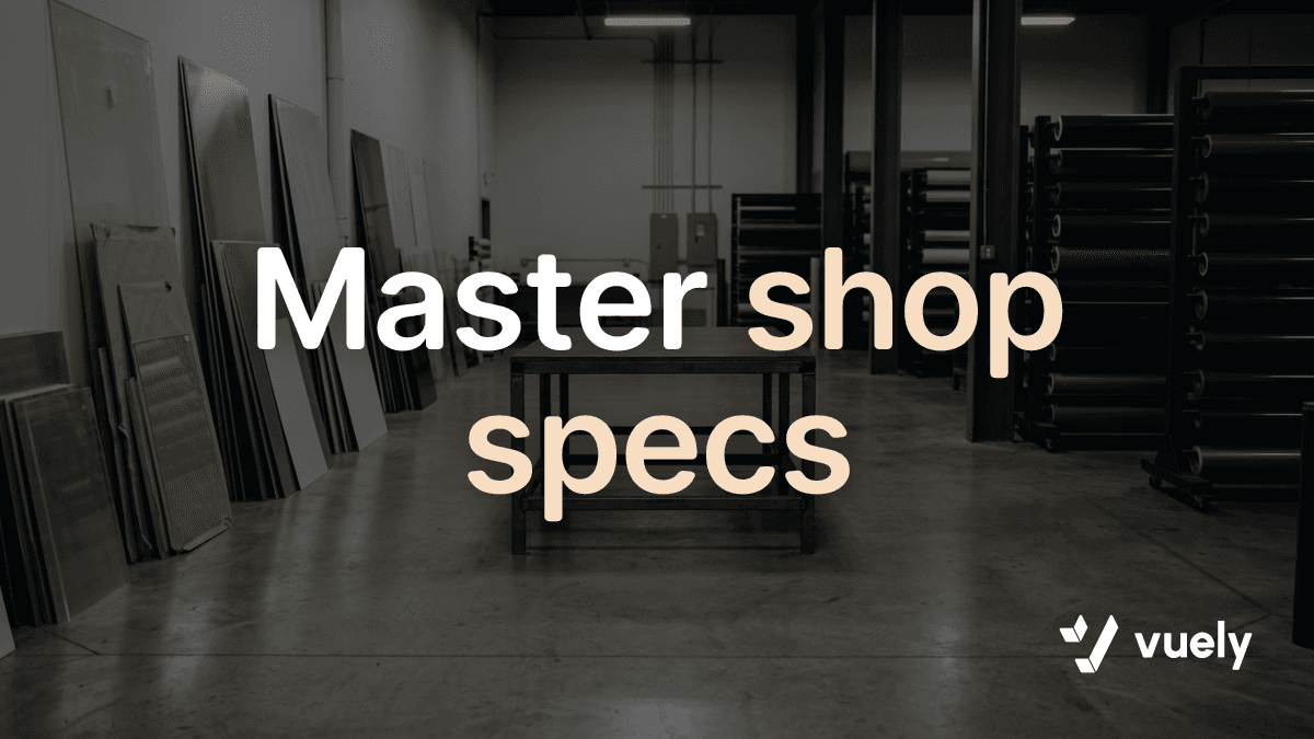 Master shop specs. A quiet sign shop interior showing stacked sheet stock against a wall and rolls of vinyl on racks behind a clear work table.